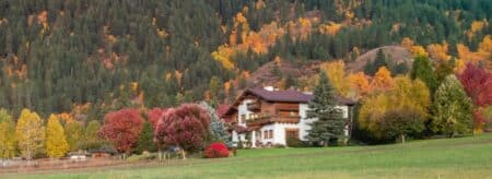 Large home with old world charm nestled at base of mountains covered in fall colored leaves