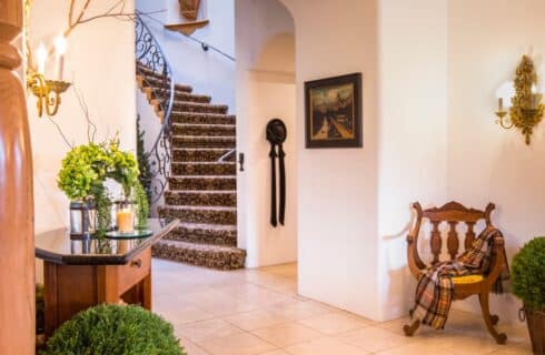 Front foyer of a large home with white walls, arched doorway into a curved staircase with a decorative wrought iron railing