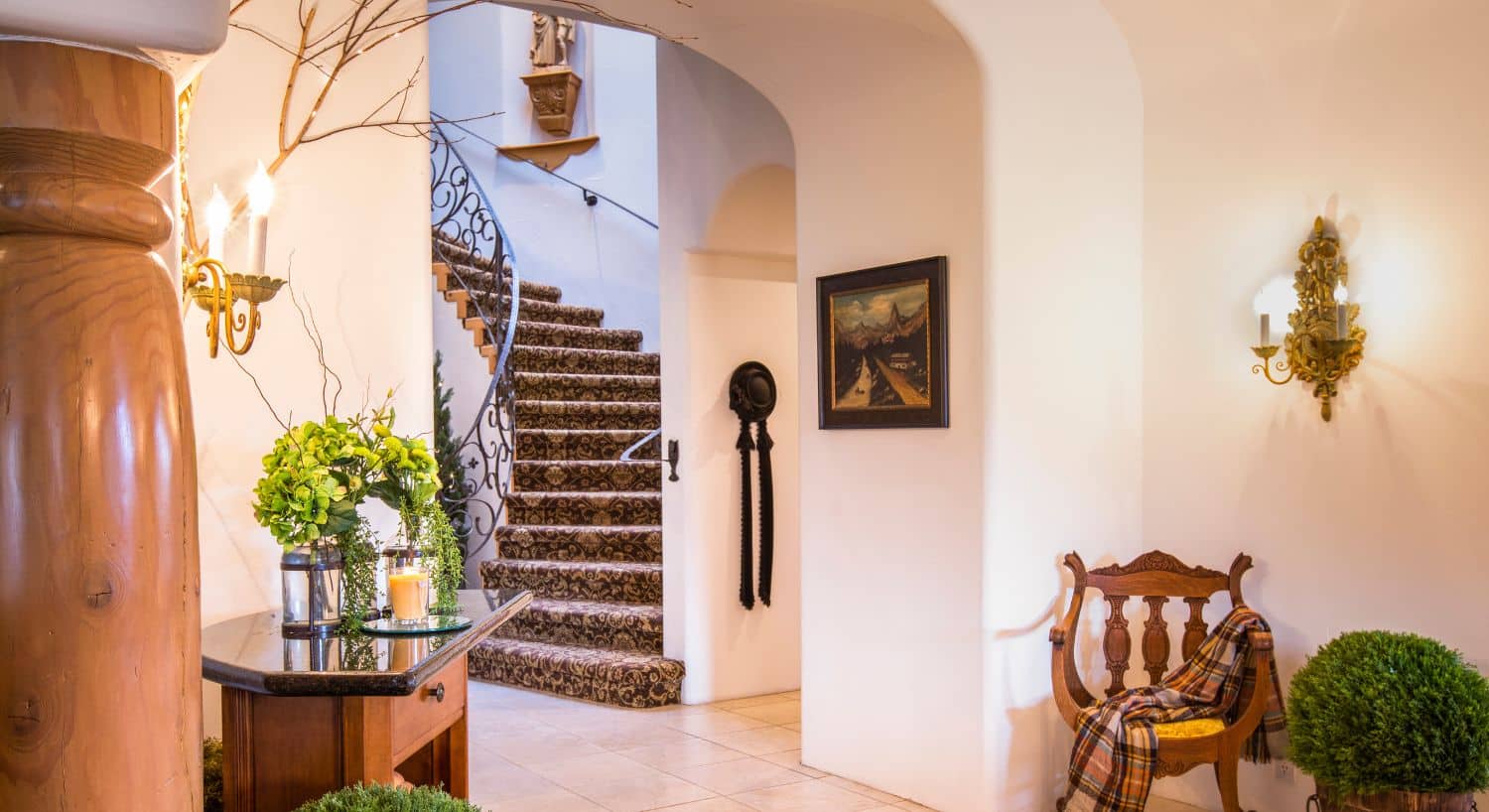 Front foyer of a home with arched doorway leading to a curved staircase with decorative wrought iron railing