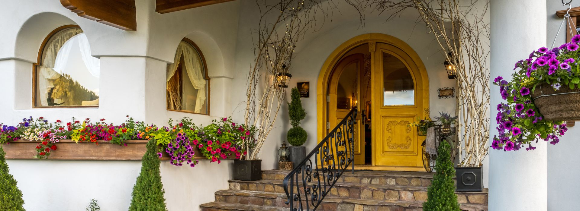 Stone steps leading up to a large golden arched doorway of a luxurious white home in old world style architecture