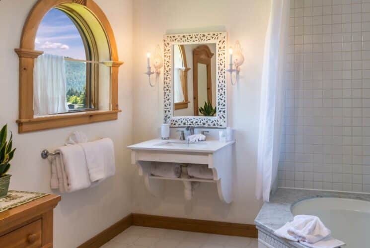 Bathroom with corner soaker tub, sink with decorative mirror and large arched window