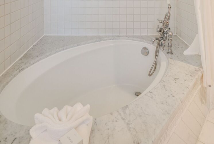 Oval soaking tub with silver faucet in the corner of a bathroom