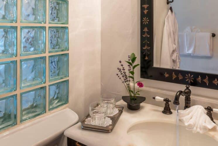 Bathroom with sink, decorative framed mirror and glass block wall