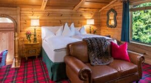 Cozy bedroom with wood paneling, plaid carpet, leather loveseat and large window