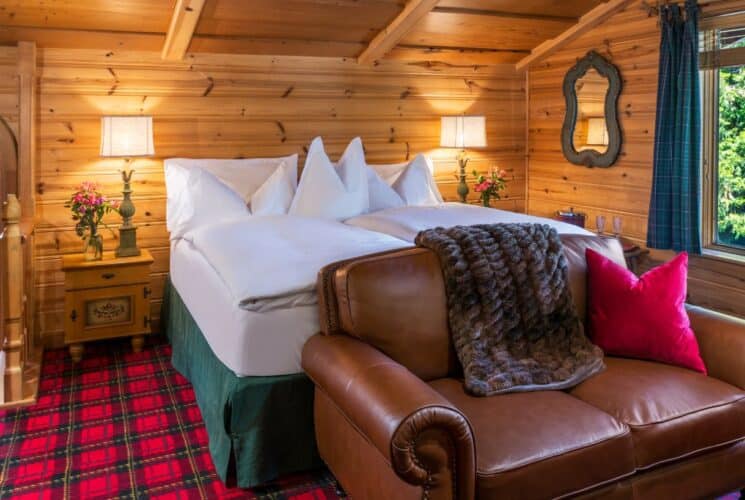 Cozy bedroom with wood paneling, plaid carpet, leather loveseat and large window